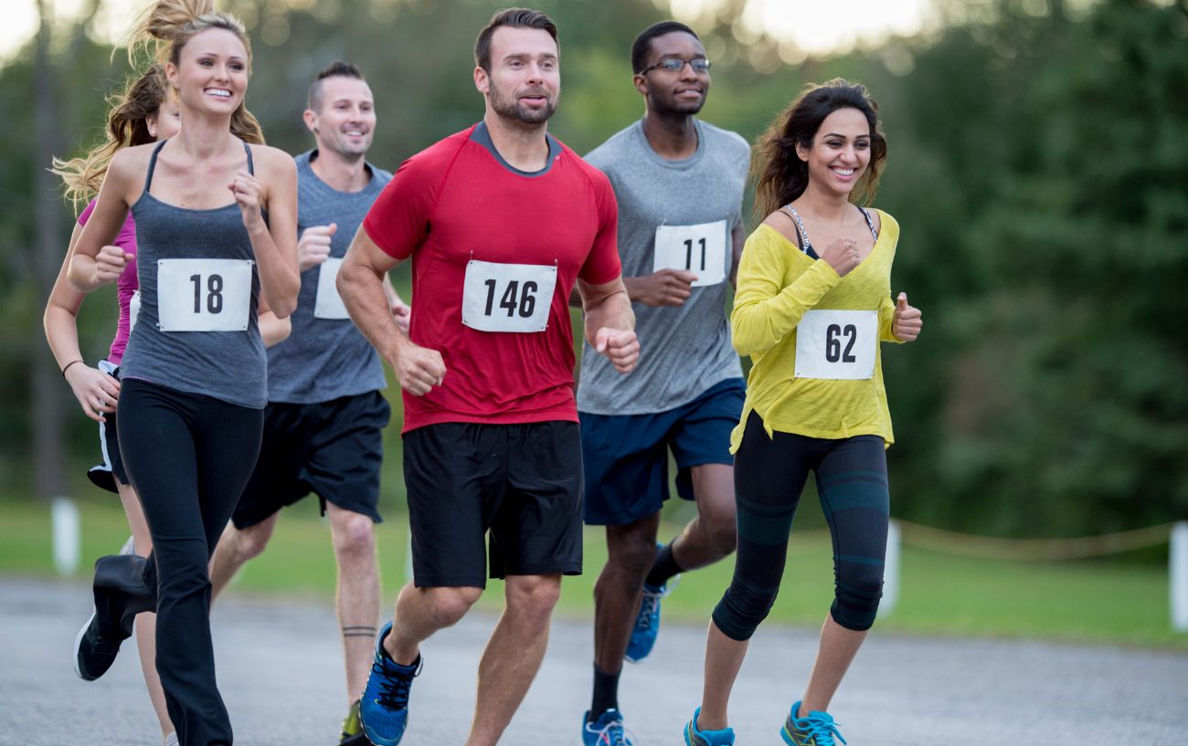 Un grupo de personas sonriendo mientras corren una carrera de 10k. 