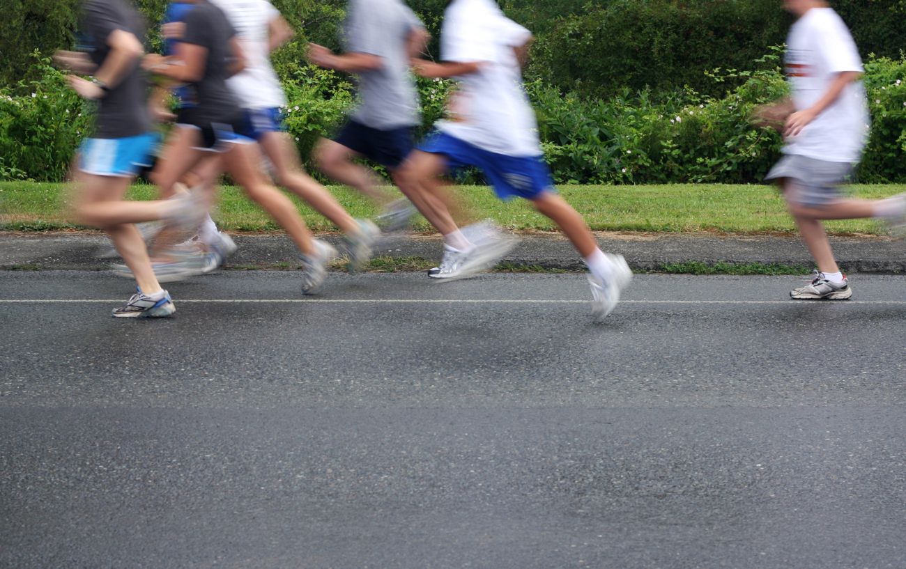 Gente corriendo rápido en la carretera mientras sus piernas están borrosas. 