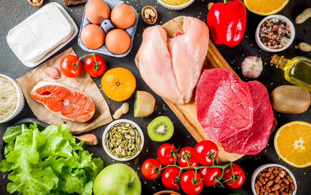 Una variedad de alimentos saludables como carne, pollo, frutas, verduras, aceites y semillas.