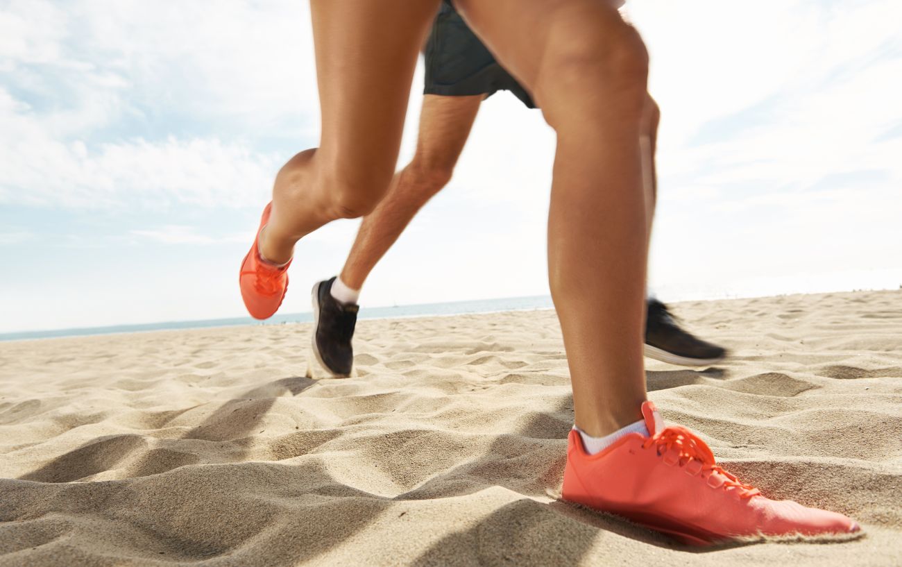 Dos personas corriendo en la arena, lo que afectará el tiempo que se tarda en correr una milla.