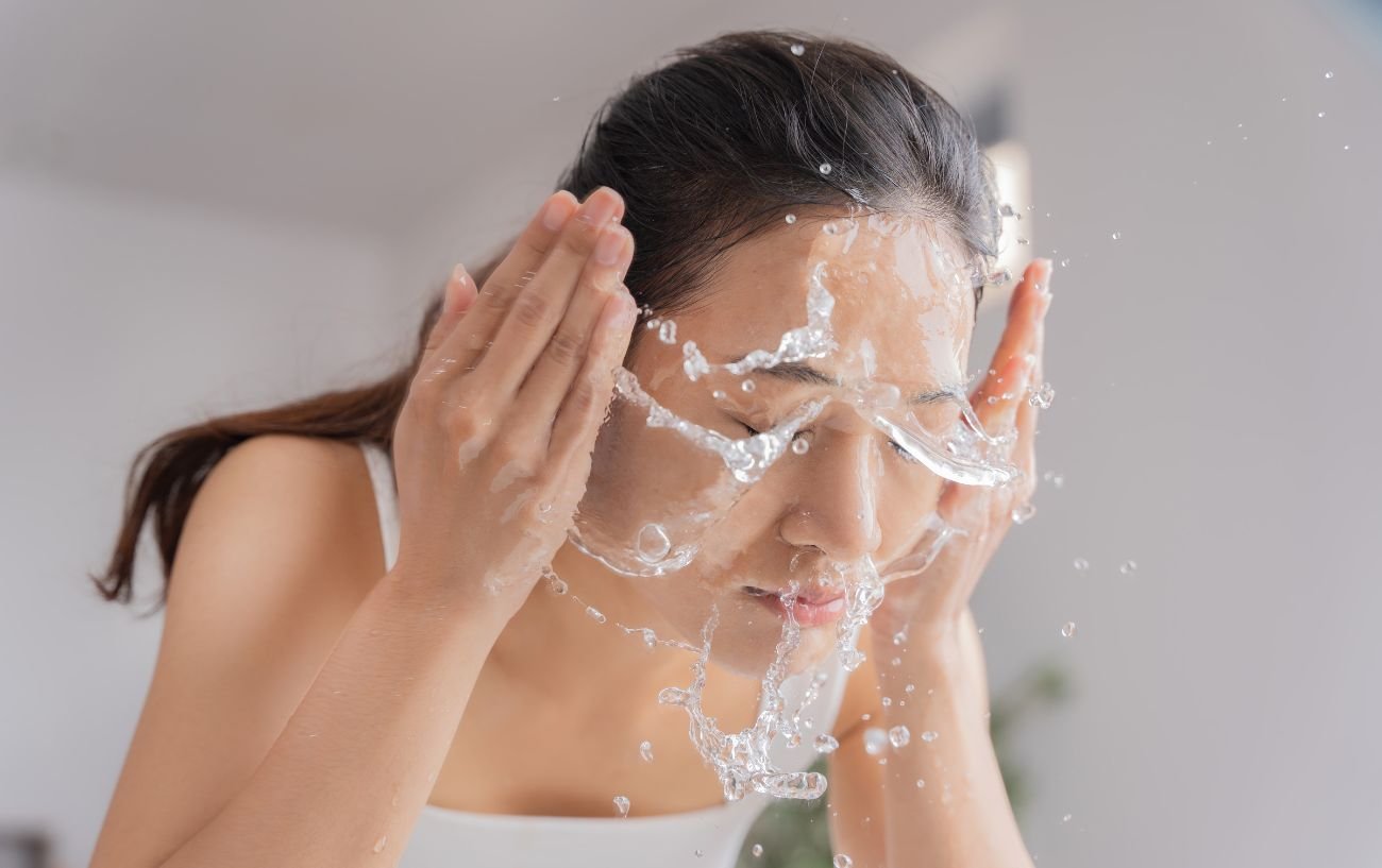 Una persona echándose agua en la cara.