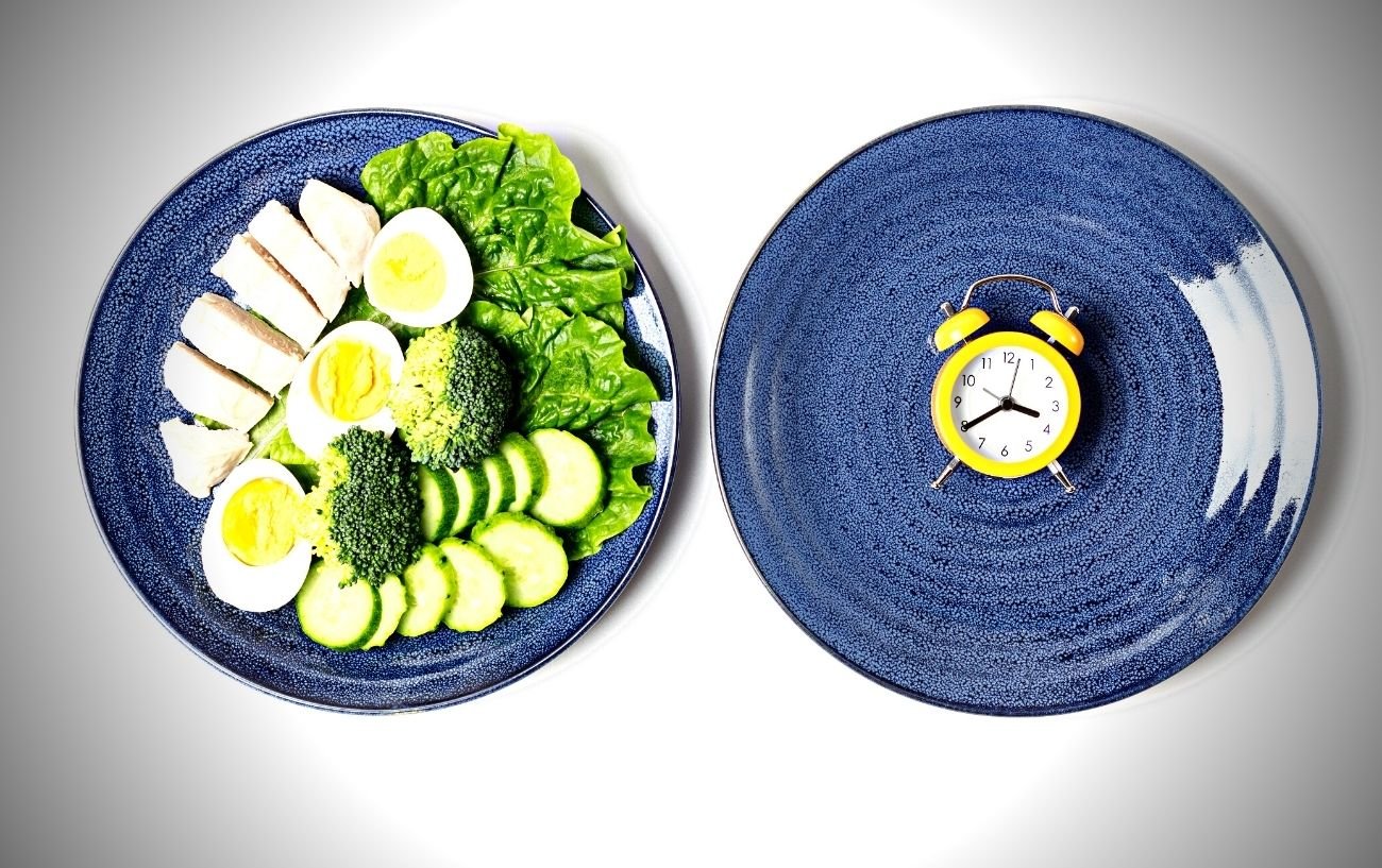 Un plato de comida junto a un plato vacío con un reloj. 