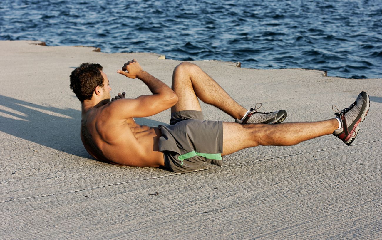 Una persona haciendo abdominales en bicicleta en la playa.