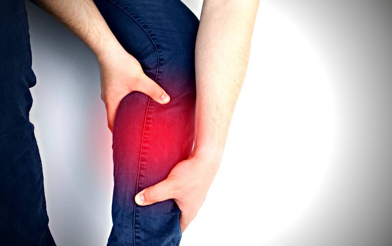 Una persona sosteniendo su músculo de la pantorrilla.  El dolor es evidente porque la pantorrilla está resaltada en rojo. 