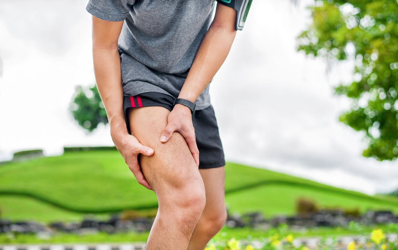 Un corredor sosteniendo su pierna dolorida. 
