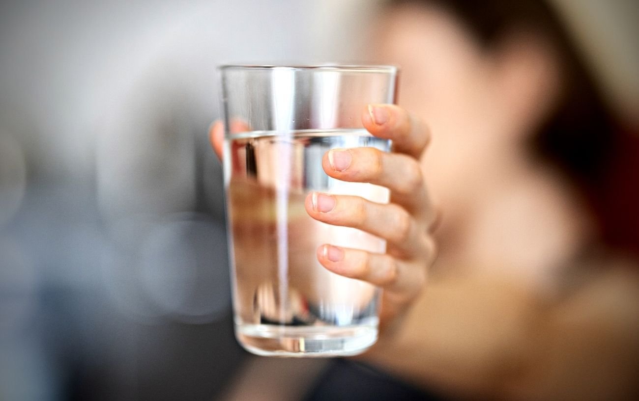 Una persona sosteniendo un vaso de agua.