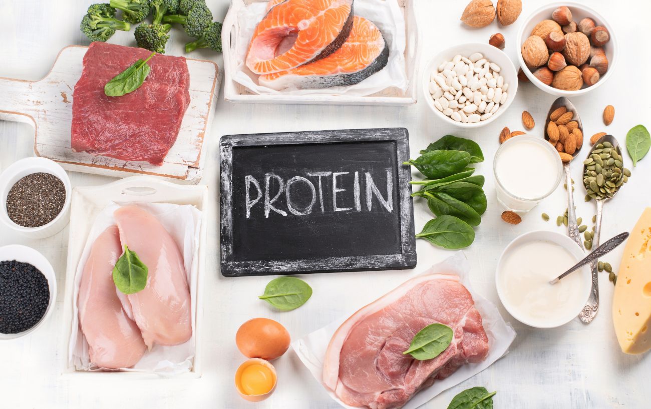 Una variedad de alimentos ricos en proteínas como pollo, carne de res, productos lácteos y nueces.