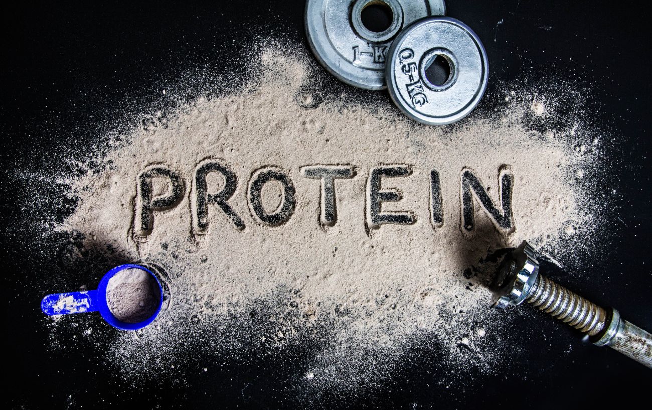 La palabra proteína grabada en polvo de proteína se extendió por el suelo.