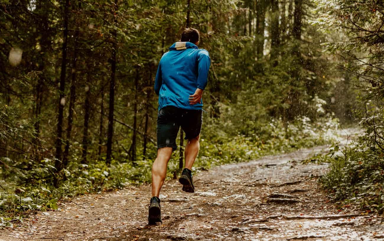 hombre corriendo en un bosque con una chaqueta reflectante para correr
