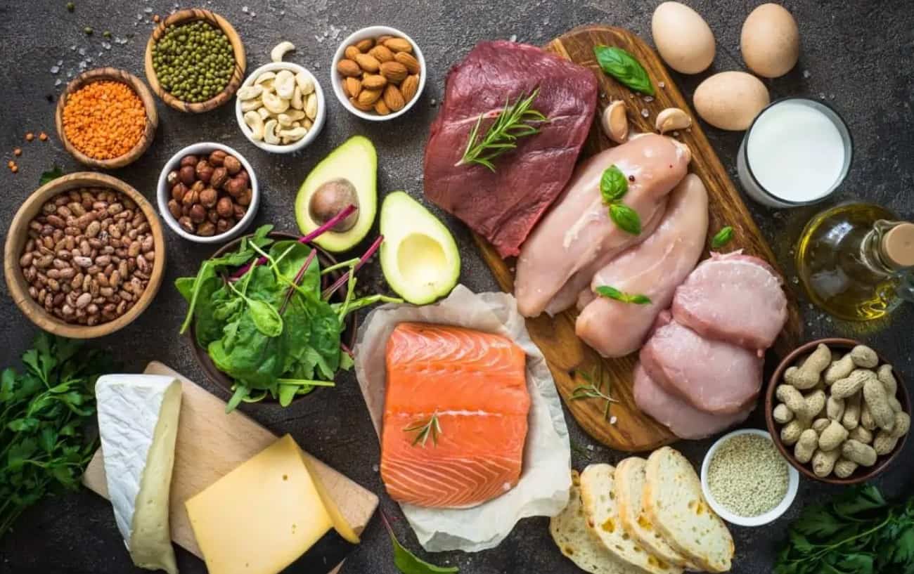 Una variedad de alimentos ricos en proteínas que incluyen carne, pescado, nueces, queso, huevos, leche, aguacate y legumbres.
