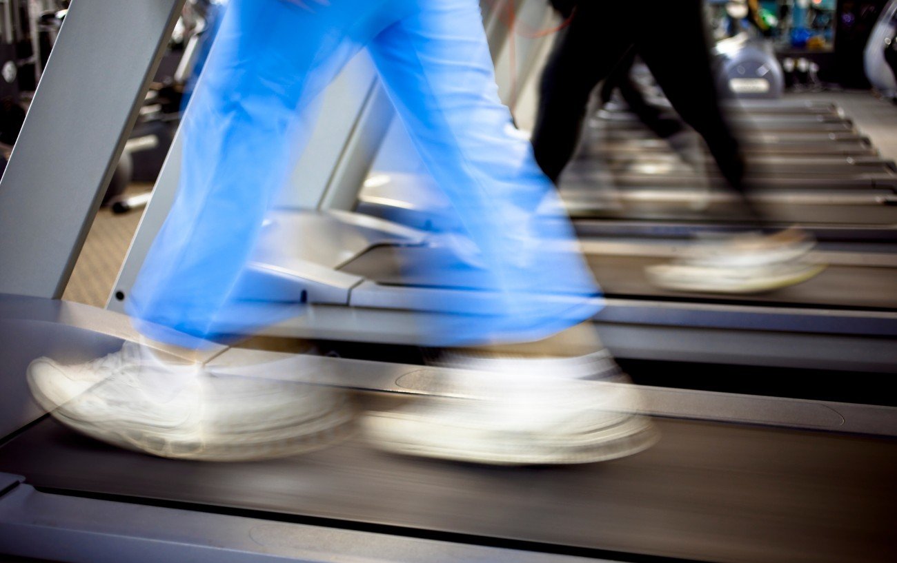Personas haciendo ejercicio en cintas de correr, un primer plano de sus pies moviéndose rápidamente. 