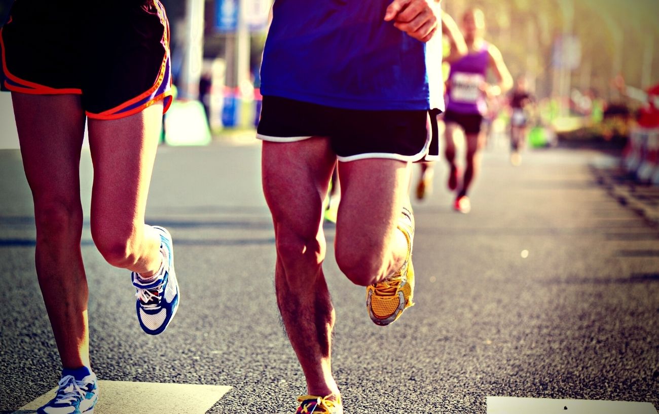 Gente corriendo una carrera en carretera, un primer plano de sus piernas.
