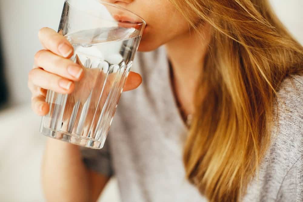 una mujer bebiendo un vaso de agua
